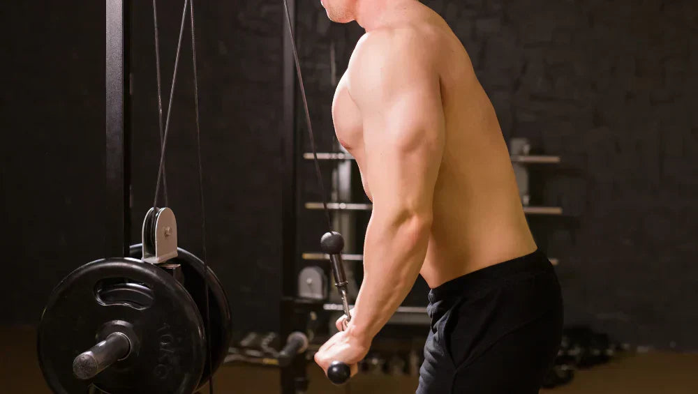 Homme musclé torse nu en train de faire un exercice triceps à la poulie dans une salle de sport